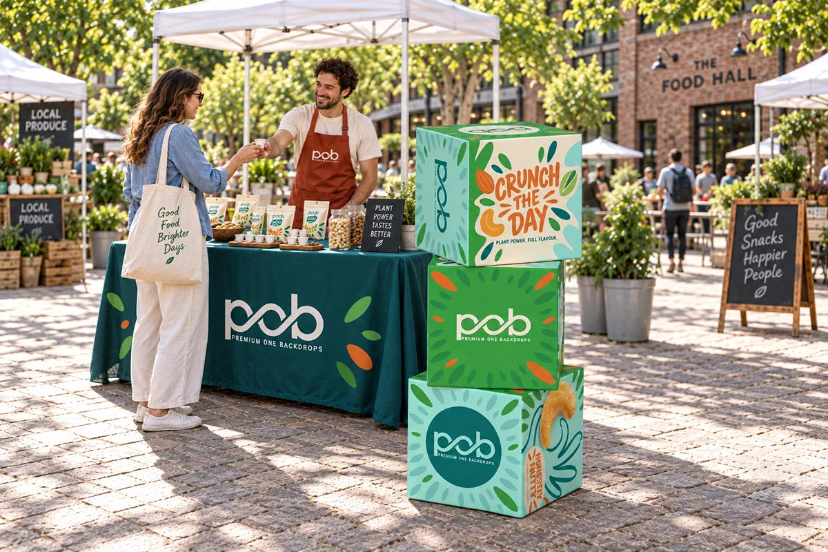 Three stacked promotional cube displays beside a branded table at an outdoor market